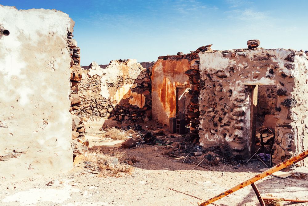 Dilapidated old buildings in mountain desert under cloudy sky