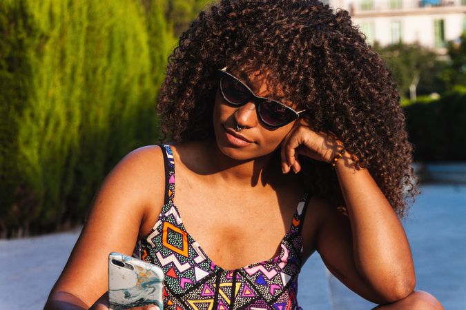 Stylish Black woman using smartphone on street