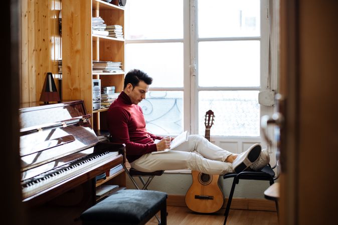 Songwriter with notebook by a window