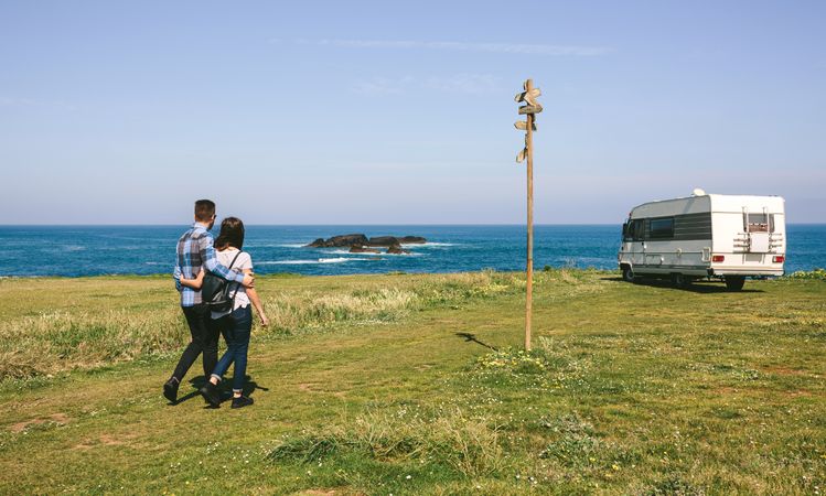 Couple taking a walk near the coast with a camper