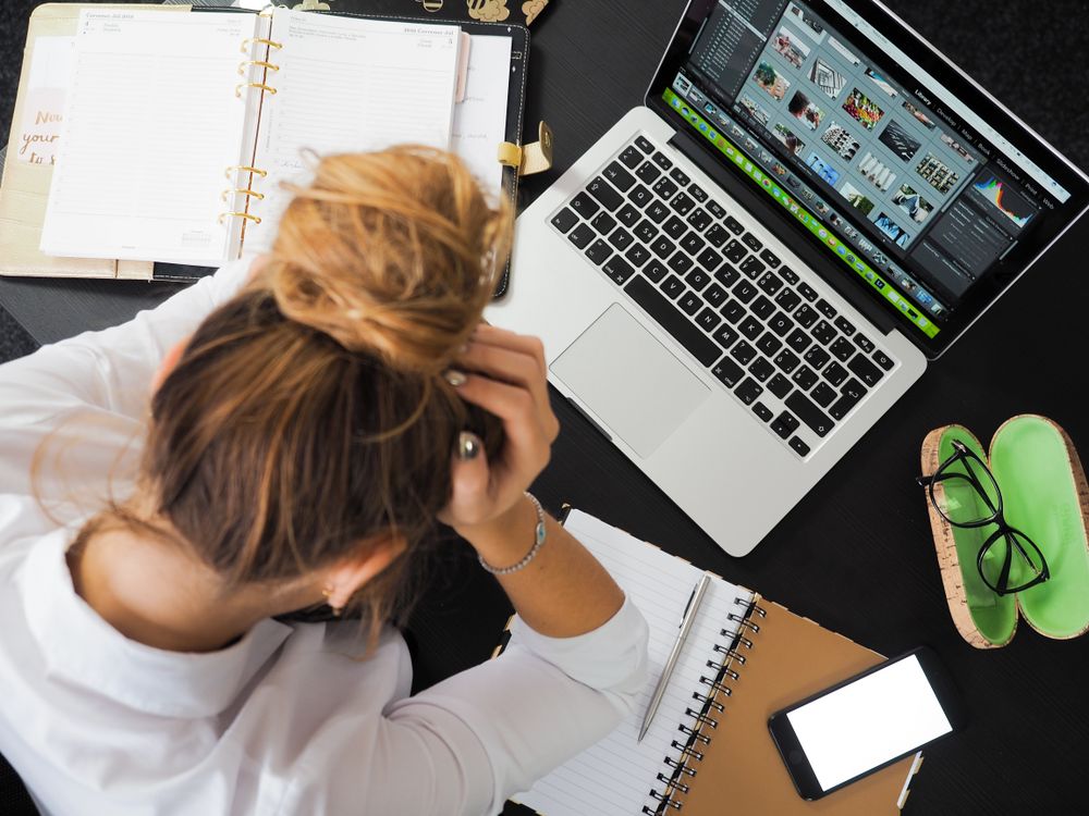 Woman leaning in exhaustion beside laptop