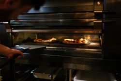 Pizza man checking pizzas in the oven