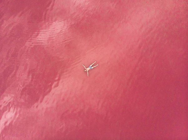 Carefree man on vacation delighting in pink water of lake