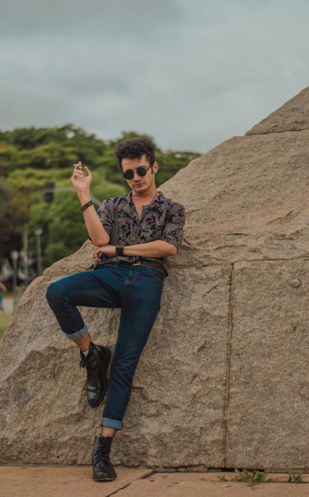 Young man with sunglasses leaning on rock