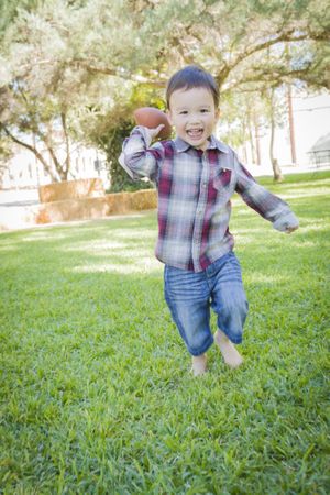 Cute Young Boy Playing Football Outside
