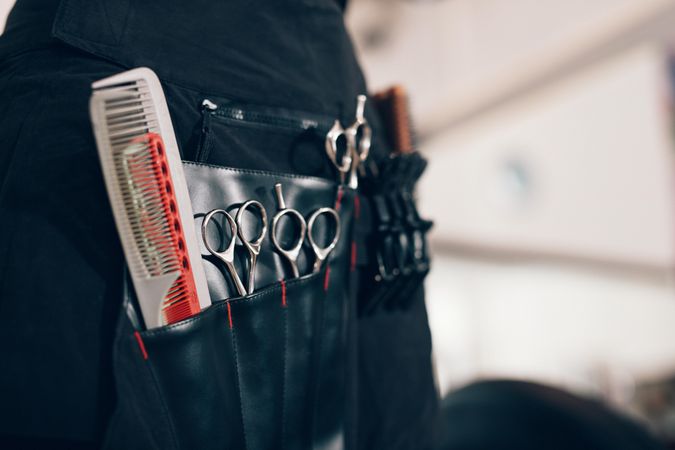 Closeup of scissors and combs in salon holster pouch