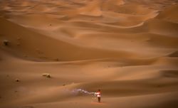 Happy woman holding firework in desert