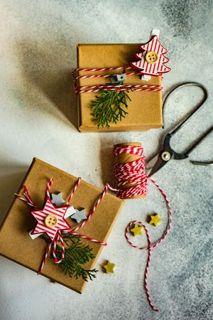 Top view of two brown Christmas presents with tree and star decorations, scissors and string