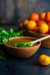 Bowl of plums and fresh parsley with Georgian Tkemali Sauce on dark table