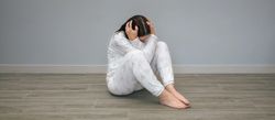 Sad unrecognizable woman sitting on floor