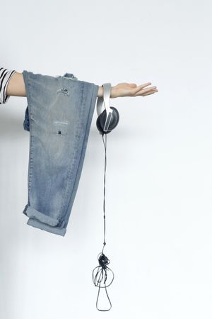 Jeans and headphones hanging off outstretched arm, vertical