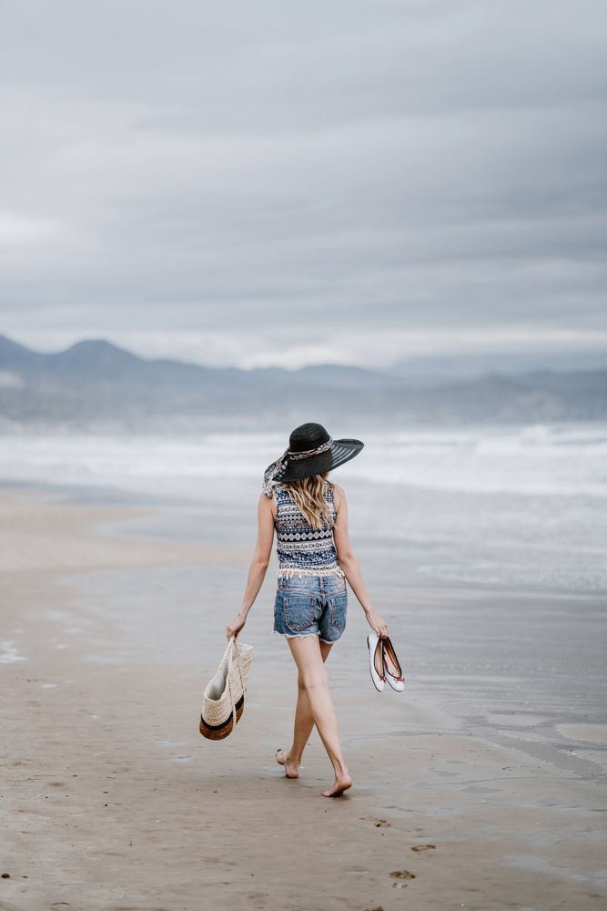 Young female walking barefoot on sandy beach