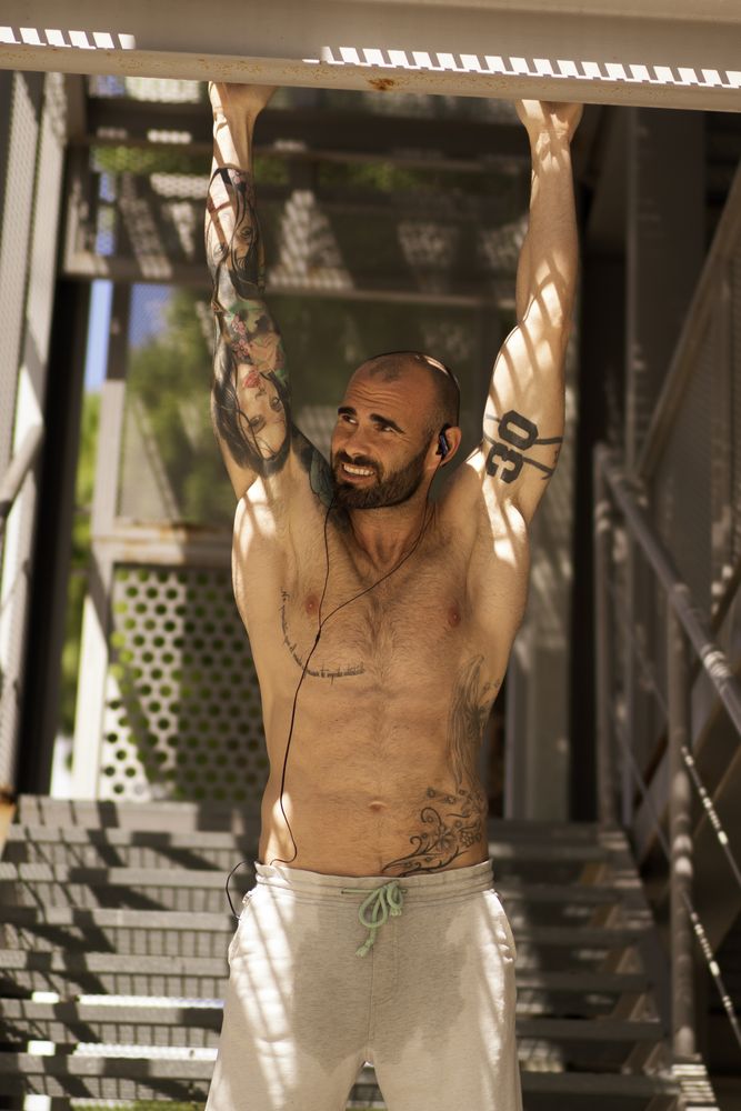 Muscular guy performing pull ups on street