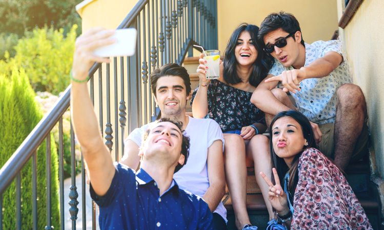 Young happy people taking a selfie with smartphone on steps outside