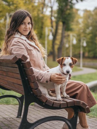 Woman sitting beside dog on wooden bench