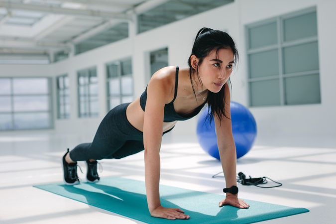 Strong woman doing push ups on mat in gym
