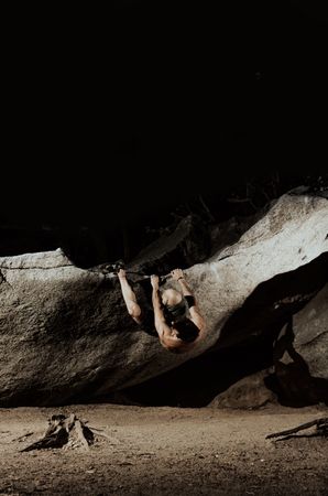 Man practicing rock climbing among large rocks in a forest