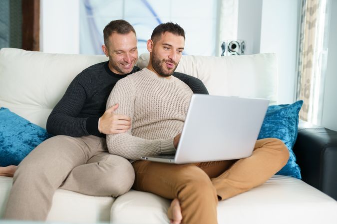 Two men chilling on sofa with laptop