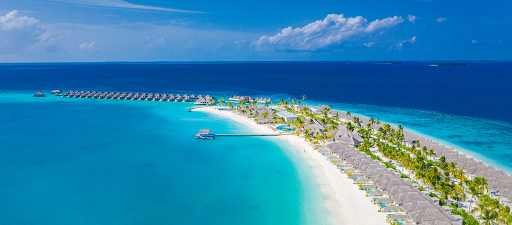 Wide shot of Maldives beach with holiday villas, wide