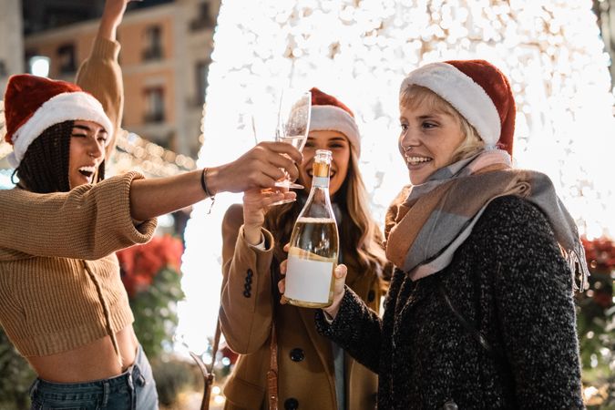 Three excited friends toasting with champagne at a vibrant Christmas party.