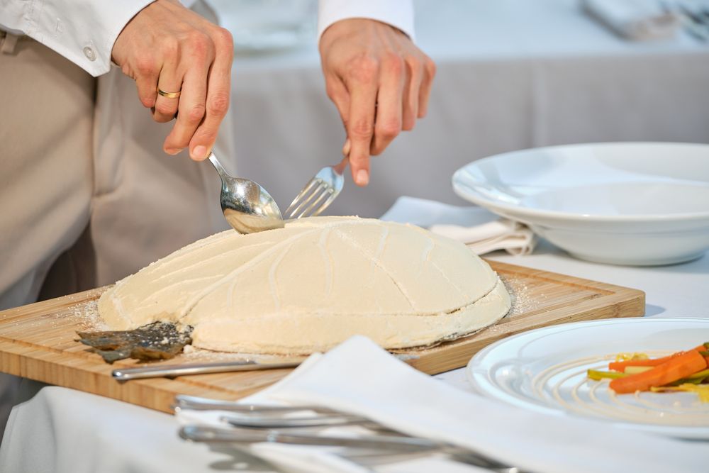 Unrecognizable chef serving fish baked in salt crust