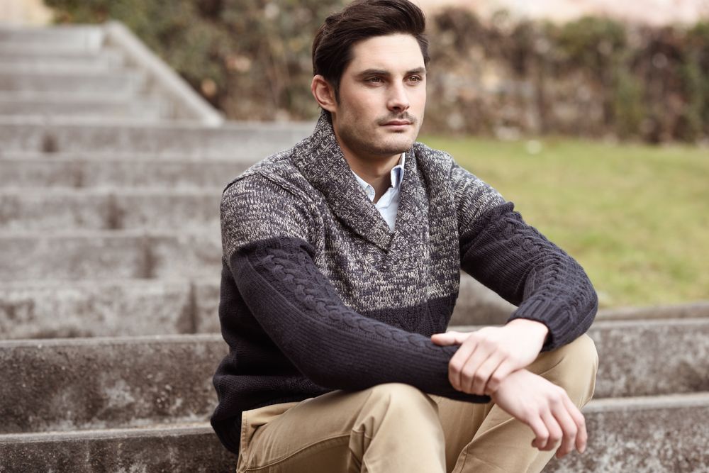 Man in winter sweater and khakis sitting on stairs outside
