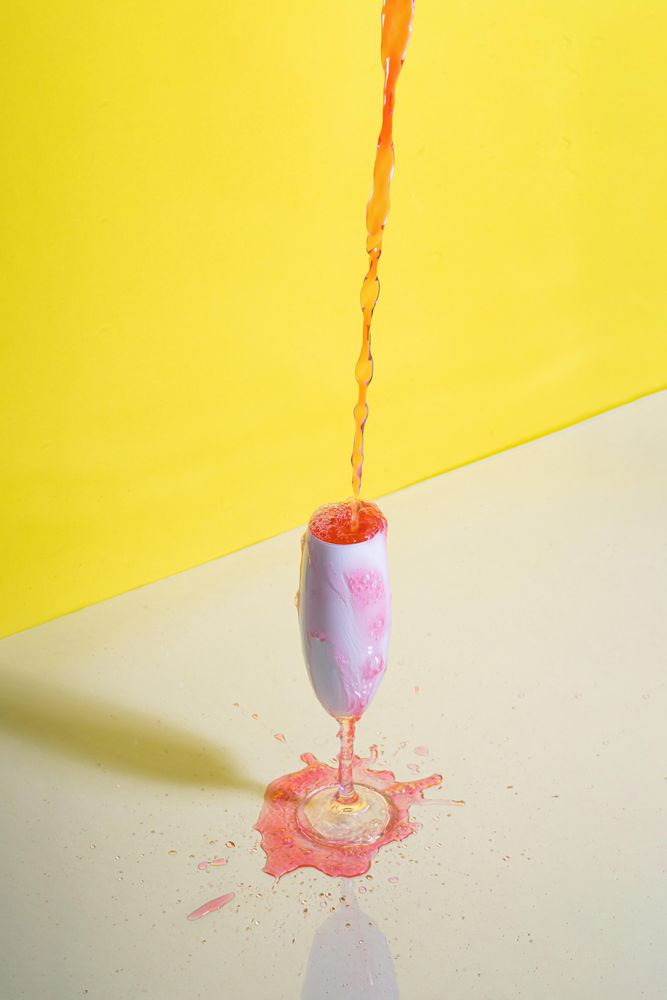 Rose champagne poured into glass against yellow background