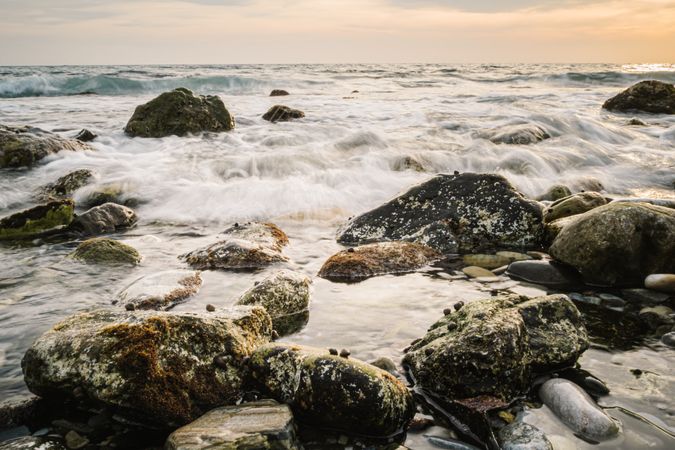 Stony seashore and waves at beautiful sunset