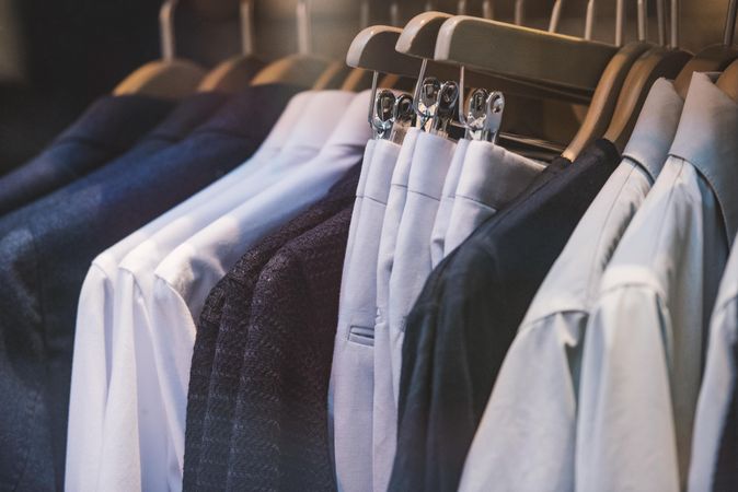 Clothes rack of dress shirts and blazers and pants in fashion store