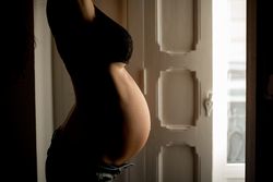 Crop pregnant woman near open door