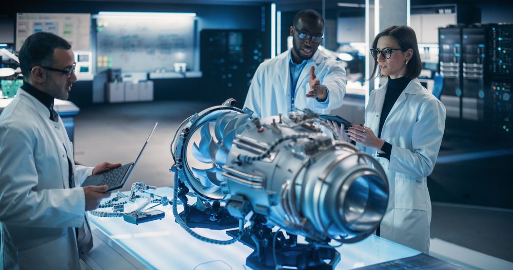 Airplane Engine Engineer and Scientist Work on a Futuristic Turbine Motor, Standing with Tablet Computer in Scientific Technology Lab.