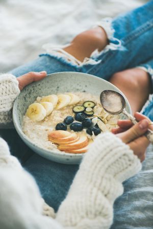 Female holding bowl of homemade oatmeal with fruits and berries