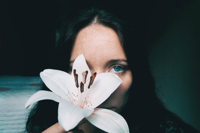 Portrait of woman with blue eyes holding lily flower