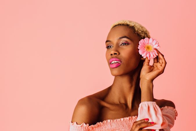Black woman with short blonde hair with pink flower in hair