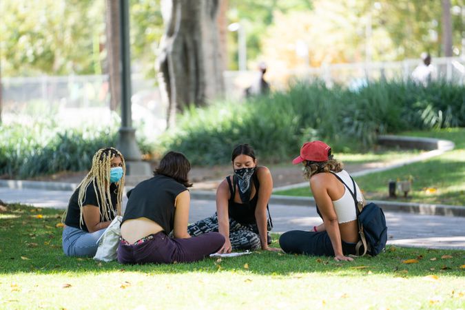 Los Angeles, CA, USA — June 16th, 2020: four women sitting on grass discussing solutions at rally