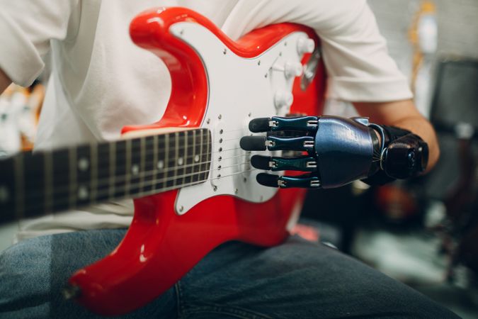 Cropped image of a person with prosthetic hand playing the electric guitar
