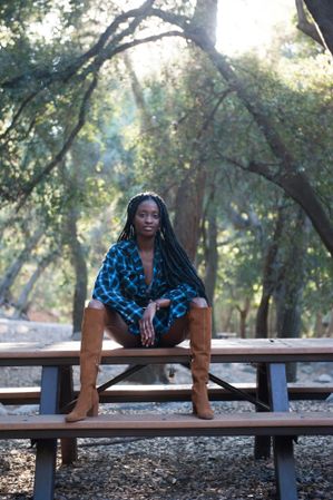 Confident Black woman sitting on bench with her hands resting on her knees