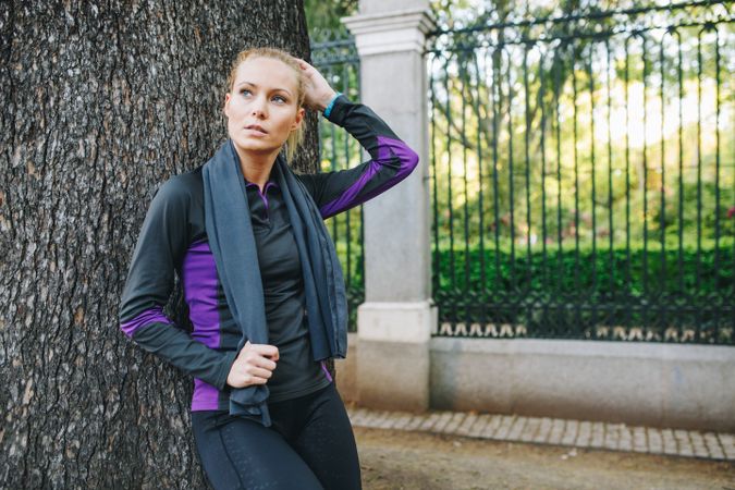 Woman resting on tree trunk after jogging