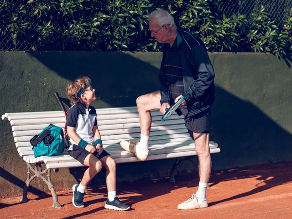 Male trainer teaching boy playing tennis