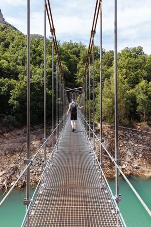 Man Crossing A Bridge In the Mountain