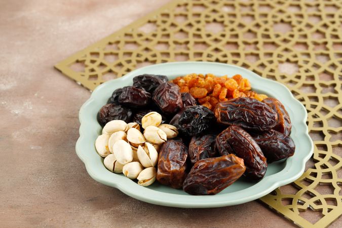 Dried fruit and nuts served on plate and patterned placemat