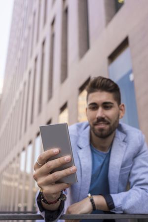 Portrait of happy man using his mobile phone standing outside
