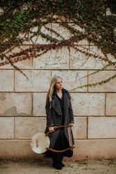 Pensive woman with lyre against brick wall