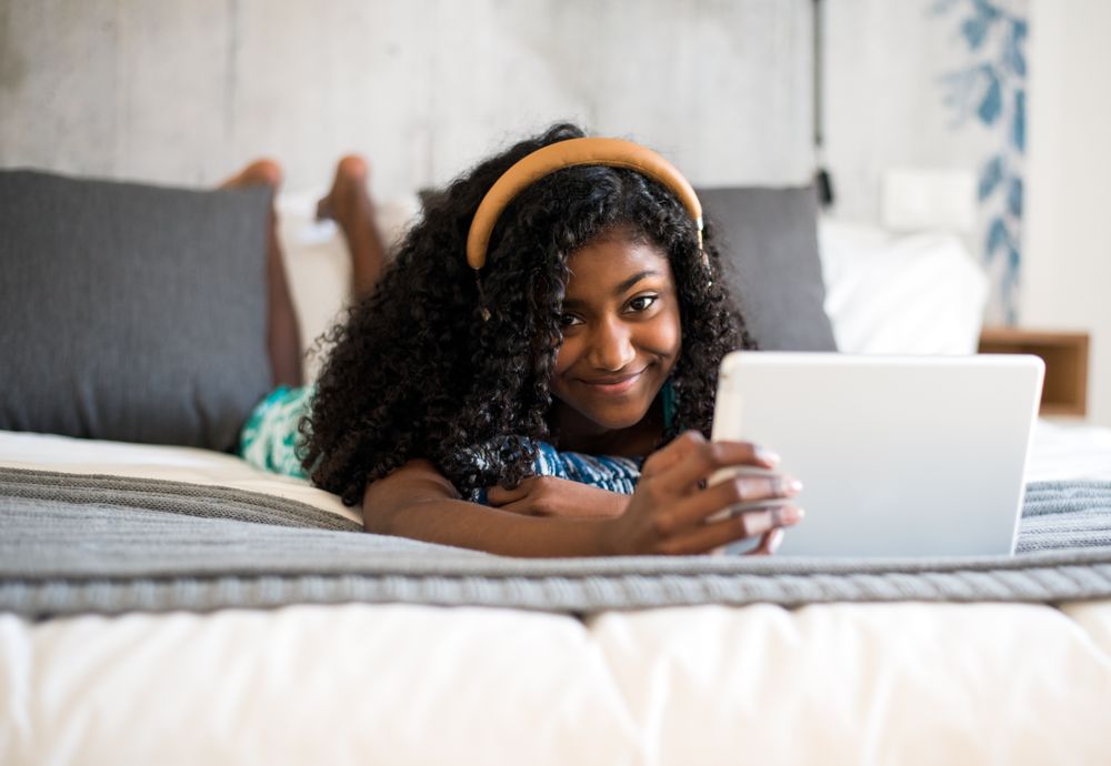 Black girl using tablet in bed