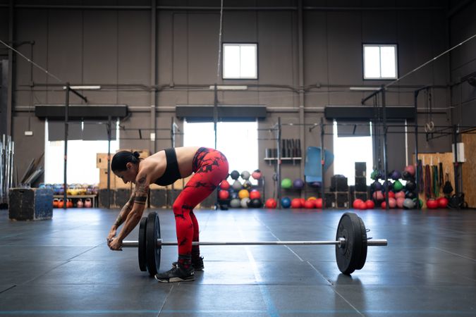 Side view of woman putting weight on bar in gym