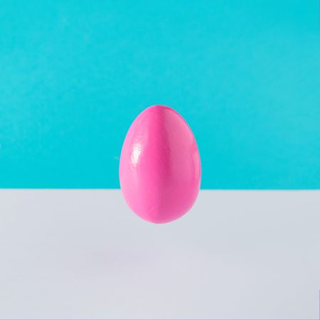 Pink egg suspended on blue background