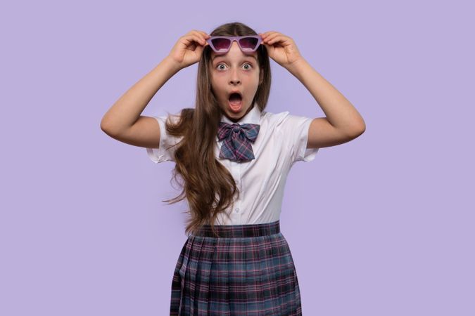 Girl wearing purple sunglasses with surprised, wide-eyed expression.