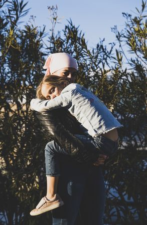 Woman holding girl with cancer headwrap
