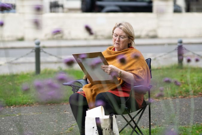 Older woman sitting and drawing in field