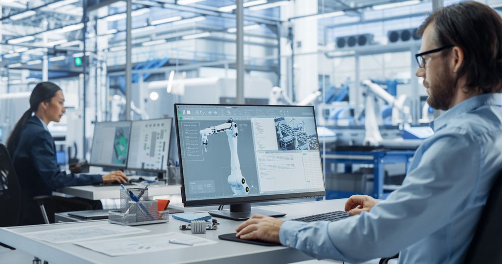 Young Asian Electronics Engineer and Automation System Administrator Working on Desktop Computers in Office. Specialists Monitoring, Analyzing Conditions at a Modern Components Manufacturing Plant